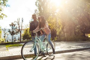 Couple biking along tree lined street. 